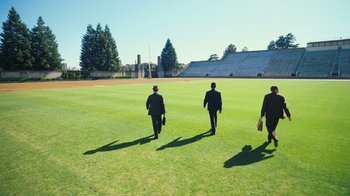Movie still from “Oppenheimer” (2023), directed by Christopher Nolan – A group of men walking across a lush green field; Extreme Wide shot, High angle