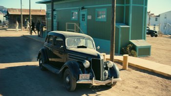 Movie still from “Oppenheimer” (2023), directed by Christopher Nolan – An old car parked on the side of the road; Extreme Wide shot, High angle