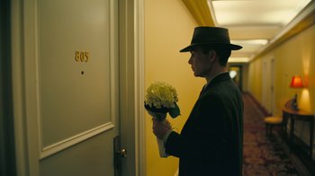Movie still from “Oppenheimer” (2023), directed by Christopher Nolan – A man holding a bouquet of flowers in his hands; Medium shot, Low angle