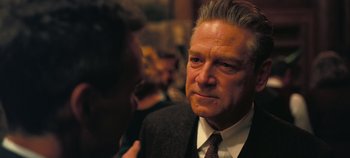 Movie still from “Oppenheimer” (2023), directed by Christopher Nolan – An older man wearing a suit and tie; Close Up shot, Over the shoulder angle