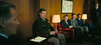 Movie still from “Oppenheimer” (2023), directed by Christopher Nolan – A man in a military uniform sitting on a chair; Wide shot, Low angle