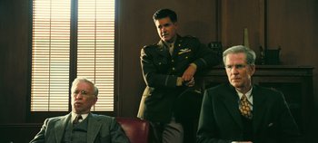 Movie still from “Oppenheimer” (2023), directed by Christopher Nolan – A man in a military uniform standing in front of two other men; Medium shot, Low angle