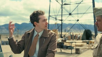 Movie still from “Oppenheimer” (2023), directed by Christopher Nolan – A man in a brown jacket and a brown tie; Medium shot, Low angle