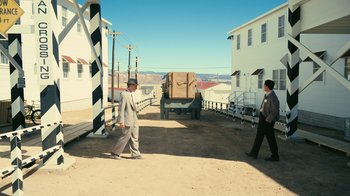 Movie still from “Oppenheimer” (2023), directed by Christopher Nolan – Two men walking down a street near a building; Extreme Wide shot, High angle
