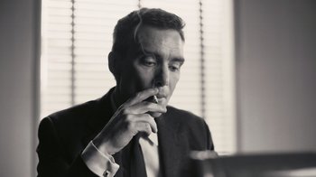 Movie still from “Oppenheimer” (2023), directed by Christopher Nolan – A black and white photo of a man smoking a cigarette; Close Up shot, Low angle