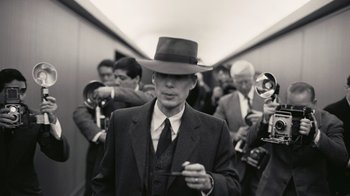 Movie still from “Oppenheimer” (2023), directed by Christopher Nolan – A black and white photo of a man in a suit and a hat; Close Up shot, Low angle