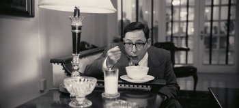 Movie still from “Oppenheimer” (2023), directed by Christopher Nolan – A black and white photo of a man sitting at a table with a bowl of soup in front of him; Medium shot, Low angle