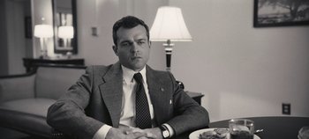 Movie still from “Oppenheimer” (2023), directed by Christopher Nolan – Black and white photograph of a man sitting at a table; Close Up shot, Low angle