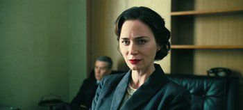 Movie still from “Oppenheimer” (2023), directed by Christopher Nolan – A woman in a business suit and a man in a suit; Close Up shot, Low angle