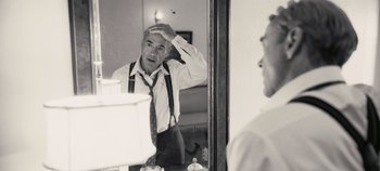 Movie still from “Oppenheimer” (2023), directed by Christopher Nolan – A black and white photo of a man in a tie looking in the mirror; Close Up shot, Over the shoulder angle