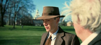 Movie still from “Oppenheimer” (2023), directed by Christopher Nolan – A man wearing a suit and hat in a park; Close Up shot, Low angle