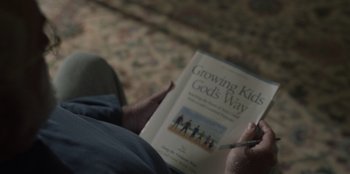 Movie still from “Our Father” (2022), directed by Lucie Jourdan – A person holding a book in their hands; Extreme Close Up shot, High angle