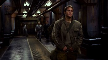 Movie still from “Pacific Rim” (2013), directed by Guillermo del Toro – A man with a backpack walking down a train platform; Medium shot, Low angle