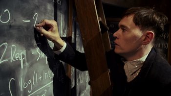A man writing on a blackboard with chalk on it