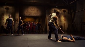 Movie still from “Pacific Rim” (2013), directed by Guillermo del Toro – A group of people standing around a man on the ground; Wide shot, Over the shoulder angle