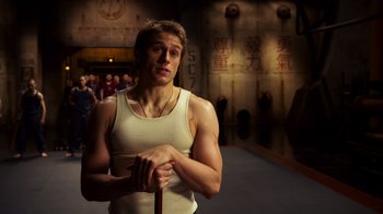 Movie still from “Pacific Rim” (2013), directed by Guillermo del Toro – A man in a white tank top holding a cane; Medium shot, Low angle