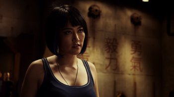 Movie still from “Pacific Rim” (2013), directed by Guillermo del Toro – A woman in a blue tank top is standing in front of a wall; Close Up shot, Over the shoulder angle