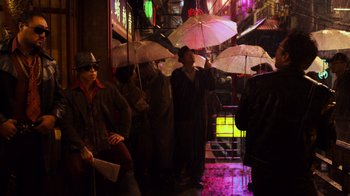 Movie still from “Pacific Rim” (2013), directed by Guillermo del Toro – A group of people sitting under umbrellas on a rainy night; Wide shot, Low angle