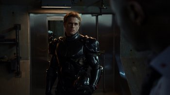 Movie still from “Pacific Rim” (2013), directed by Guillermo del Toro – A man in a black suit standing next to a metal door; Medium shot, Over the shoulder angle