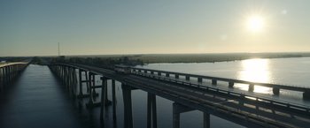 Movie still from “Palmer” (2021), directed by Fisher Stevens – A train on a bridge over a body of water; Extreme Wide shot, Low angle