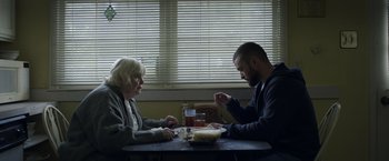 Movie still from “Palmer” (2021), directed by Fisher Stevens – A man and a woman sitting at a dinner table; Medium shot, Over the shoulder angle