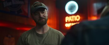Movie still from “Palmer” (2021), directed by Fisher Stevens – A man with a beard wearing a baseball cap; Close Up shot, Over the shoulder angle