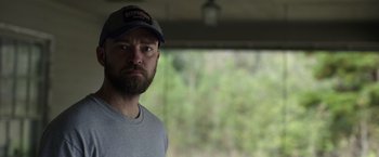 Movie still from “Palmer” (2021), directed by Fisher Stevens – A man with a beard wearing a hat; Close Up shot, Over the shoulder angle