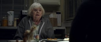 Movie still from “Palmer” (2021), directed by Fisher Stevens – An older woman sitting at a table with a plate of food in front of her; Close Up shot, Over the shoulder angle