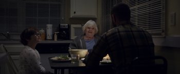 Movie still from “Palmer” (2021), directed by Fisher Stevens – An older woman sitting at a table with a man; Medium shot, Over the shoulder angle