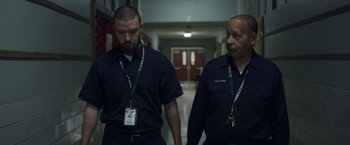 Movie still from “Palmer” (2021), directed by Fisher Stevens – Two security guards walking down a hallway in a building; Medium shot, High angle
