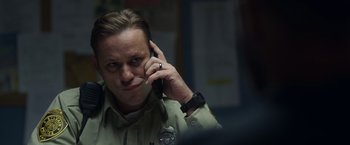 Movie still from “Palmer” (2021), directed by Fisher Stevens – A police officer talking on a cell phone; Close Up shot, Low angle