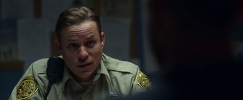 Movie still from “Palmer” (2021), directed by Fisher Stevens – A man in a police uniform looking at the camera; Close Up shot, Low angle