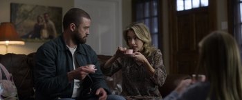 Movie still from “Palmer” (2021), directed by Fisher Stevens – A man and a woman sitting on a couch holding coffee cups; Medium shot, Over the shoulder angle