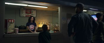 Movie still from “Palmer” (2021), directed by Fisher Stevens – A woman and a boy are standing in front of a counter; Medium shot, Over the shoulder angle