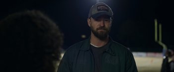 Movie still from “Palmer” (2021), directed by Fisher Stevens – A man with a beard wearing a hat and a jacket; Close Up shot, Over the shoulder angle