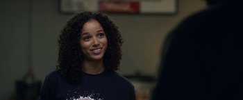 Movie still from “Palmer” (2021), directed by Fisher Stevens – A woman with curly black hair smiling for the camera; Close Up shot, Over the shoulder angle