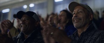 Movie still from “Palmer” (2021), directed by Fisher Stevens – A group of people sitting in a room clapping; Close Up shot, Low angle