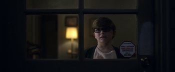 Movie still from “Palmer” (2021), directed by Fisher Stevens – A young boy wearing glasses looking out of a window; Close Up shot, Over the shoulder angle