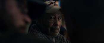 Movie still from “Palmer” (2021), directed by Fisher Stevens – An older man wearing a baseball cap looking at the camera; Close Up shot, Over the shoulder angle