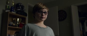 Movie still from “Palmer” (2021), directed by Fisher Stevens – A person with glasses is standing in a room; Close Up shot, Low angle
