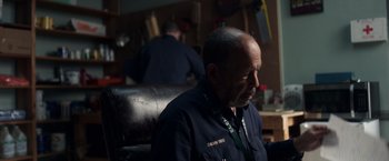 Movie still from “Palmer” (2021), directed by Fisher Stevens – A man sitting in front of another man in a room; Close Up shot, Low angle