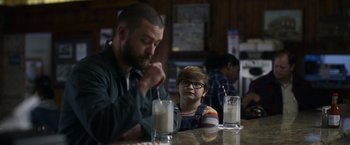 Movie still from “Palmer” (2021), directed by Fisher Stevens – A man sitting at a table next to a child; Medium shot, Over the shoulder angle
