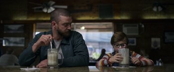 Movie still from “Palmer” (2021), directed by Fisher Stevens – A man sitting at a table with a child; Medium shot, Over the shoulder angle