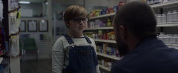 Movie still from “Palmer” (2021), directed by Fisher Stevens – A person with glasses is talking to a man in a store; Close Up shot, Over the shoulder angle