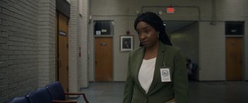 Movie still from “Palmer” (2021), directed by Fisher Stevens – A woman standing in a hallway with a badge on her lapel; Medium shot, Over the shoulder angle