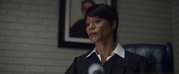 Movie still from “Palmer” (2021), directed by Fisher Stevens – A woman wearing a black robe and a white shirt; Close Up shot, Low angle