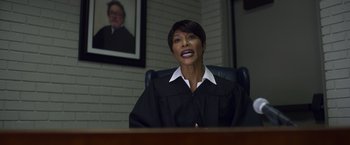 Movie still from “Palmer” (2021), directed by Fisher Stevens – A woman in a judge's robe sitting at a desk; Medium shot, Low angle
