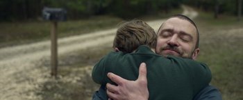 Movie still from “Palmer” (2021), directed by Fisher Stevens – A man is hugging a boy in a forest; Close Up shot, Over the shoulder angle