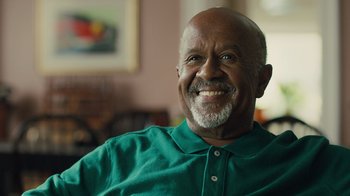 Movie still from “Atlanta” (2016), created by Donald Glover – An older man smiling for the camera in a green shirt; Close Up shot, Low angle