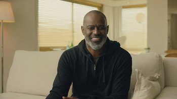 Movie still from “Atlanta” (2016), created by Donald Glover – A man sitting on top of a couch in a living room; Medium shot, Low angle